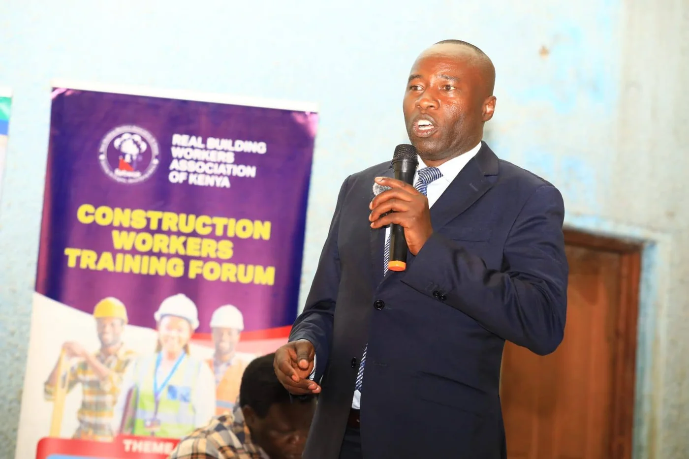 REBWAK representative speaking beside the Construction Workers Training Forum banner