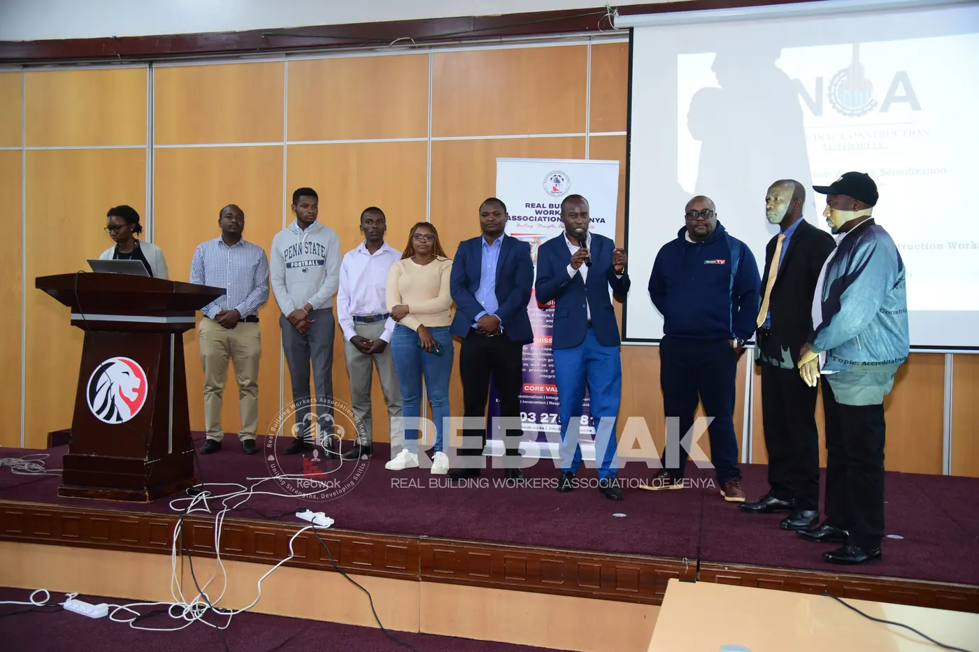REBWAK officials and guests standing on stage during the NCA accreditation presentation